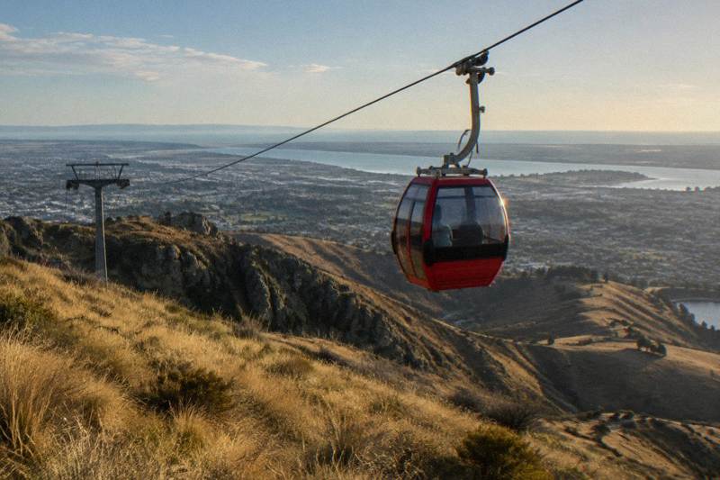 Cable car cabin gliding above coastal hills and sea views at the Christchurch Gondola